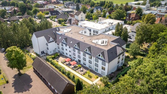 Moderne Seniorenwohnanlage mit grünem Innenhof und roten Sonnenschirmen.