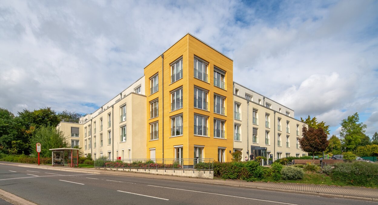 Moderne Wohnanlage mit heller Fassade und markantem gelbem Eckgebäude.