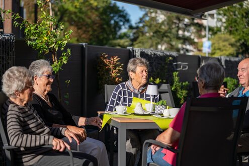 Senioren beim Kaffeetrinken auf einer Terrasse der Wohnanlage.