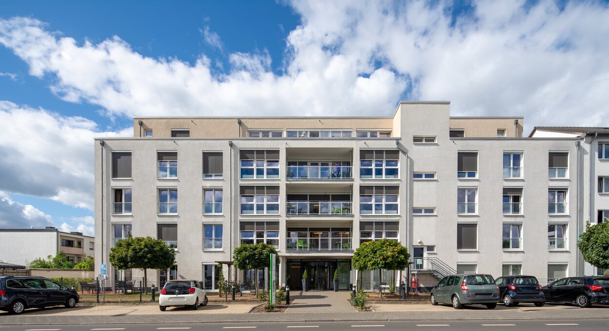 Helle, moderne Wohnanlage für betreutes Wohnen mit Balkonen und PKW-Parkplätzen.