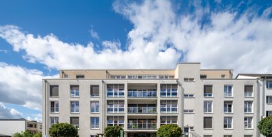 Helle, moderne Wohnanlage für betreutes Wohnen mit Balkonen und PKW-Parkplätzen.