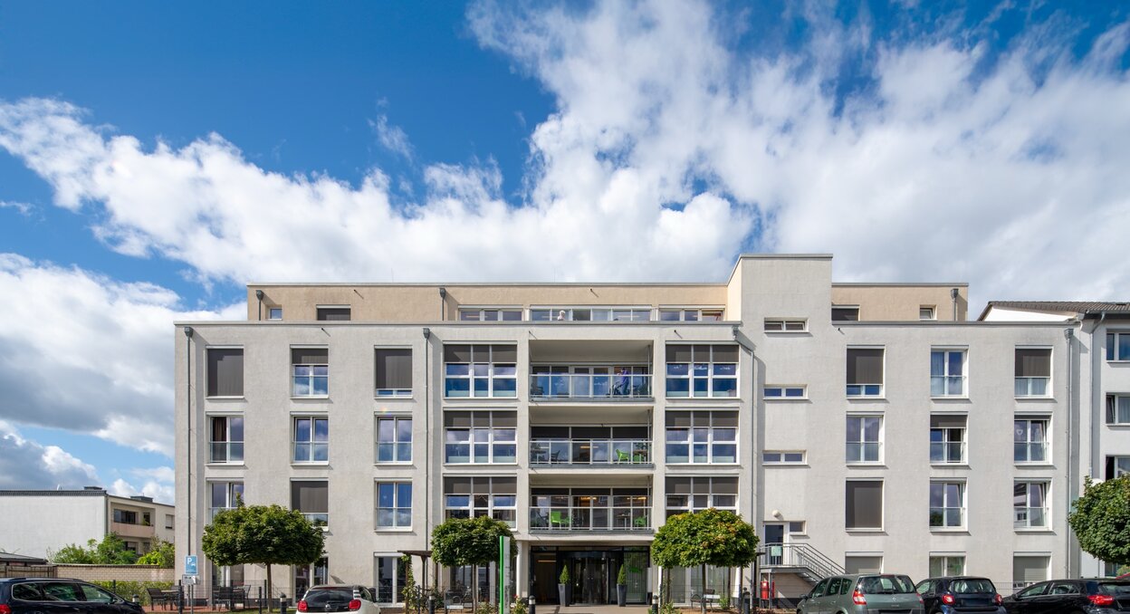 Helle, moderne Wohnanlage für betreutes Wohnen mit Balkonen und PKW-Parkplätzen.