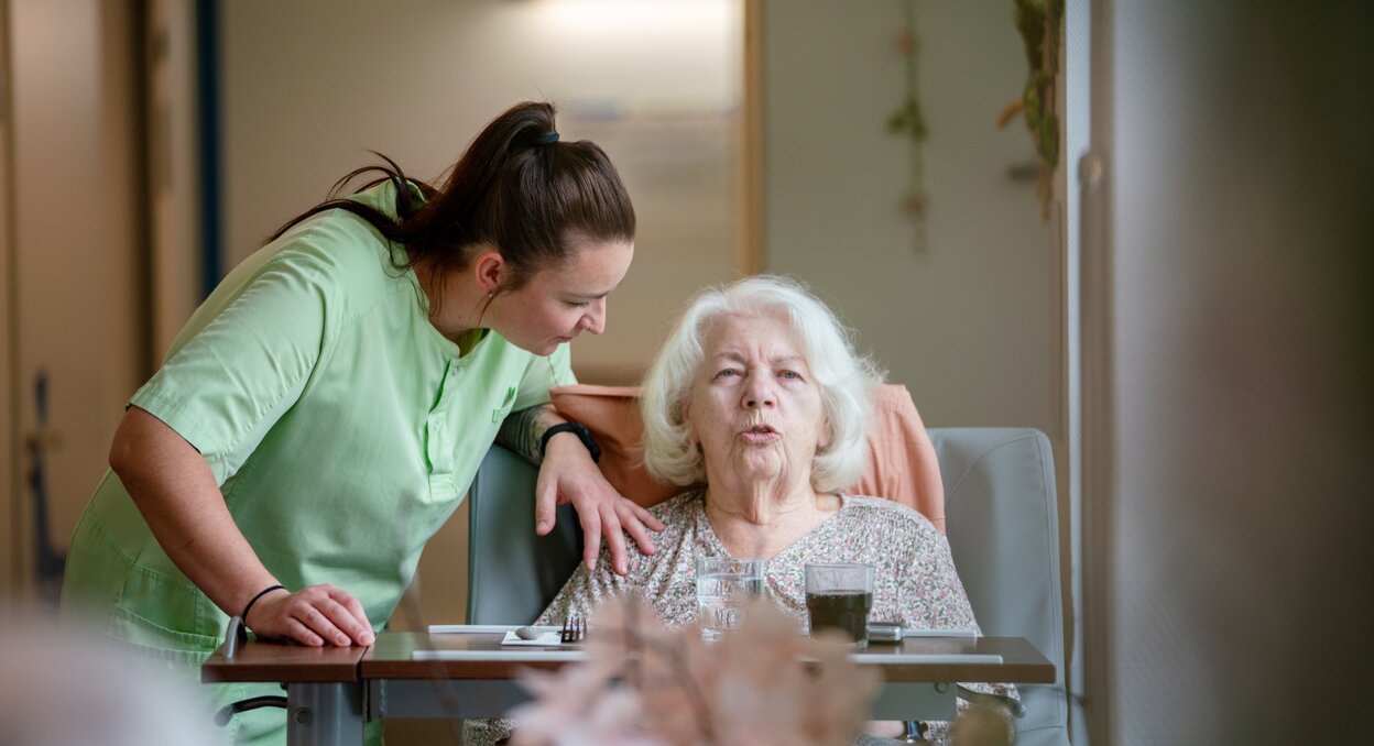 Pflegerin unterhält sich mit Seniorin in einer Einrichtung für betreutes Wohnen.