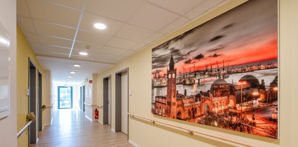 Heller Flur einer Senioren-Wohnanlage mit großem Hamburg-Wandbild und Handläufen.