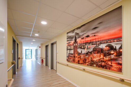 Heller Flur einer Senioren-Wohnanlage mit großem Hamburg-Wandbild und Handläufen.