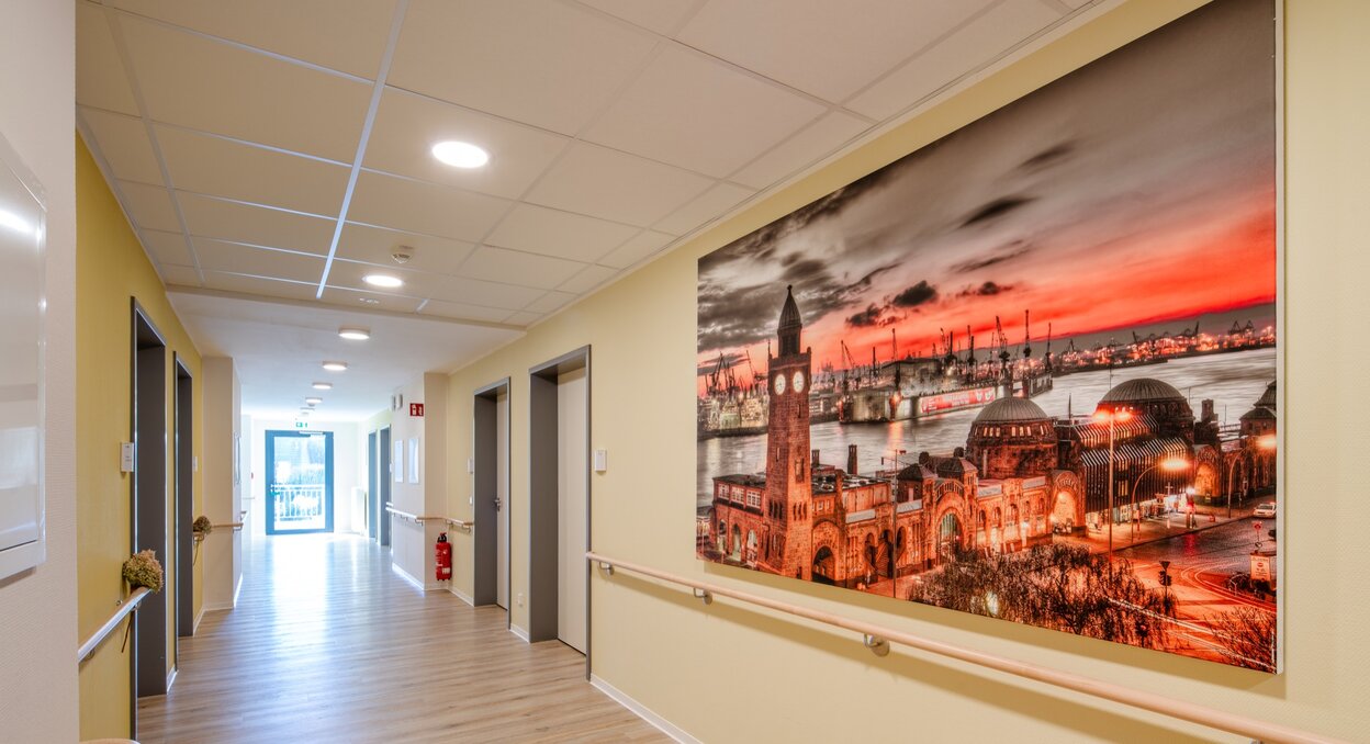 Heller Flur einer Senioren-Wohnanlage mit großem Hamburg-Wandbild und Handläufen.