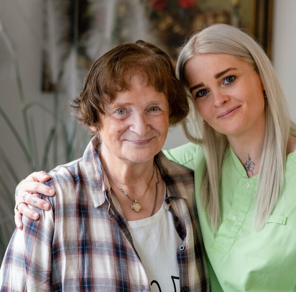 Lächelnde Seniorin und Pflegerin in einer Wohnanlage.